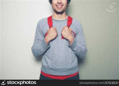Young man wearing a red backpack is standing against a green and white background