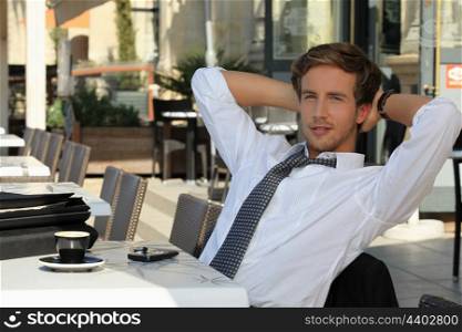young man wearing a suit and tie, relaxing on a terrace at breakfast time