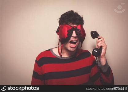Young man wearing abra on his face is answering the telephone