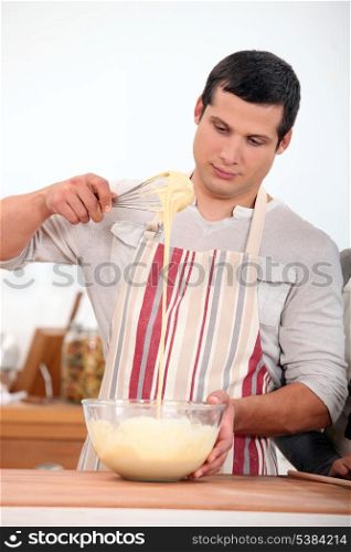 young man wearing an apron and doing dough