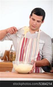young man wearing an apron and doing dough