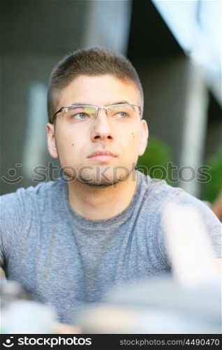 Young man wearing eyeglasses in outdoor restaurant