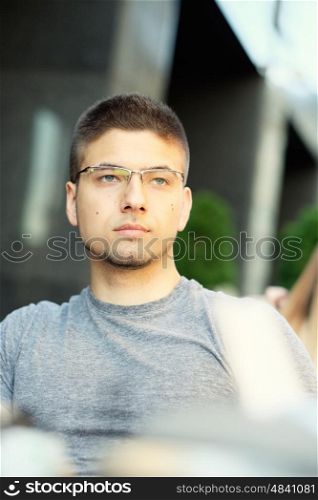 Young man wearing eyeglasses in outdoor restaurant