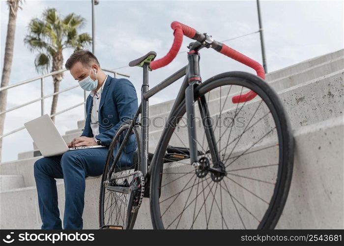 young man wearing medical mask while sitting his bike