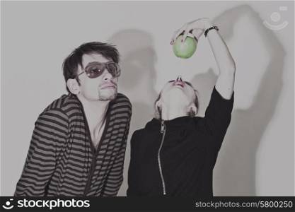 Young man wearing sunglasses and woman biting a green apple