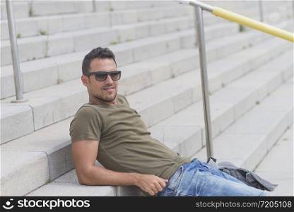 Young man wearing sunglasses sitting on stairs relaxed