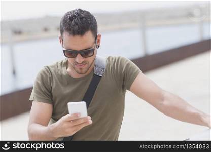 Young man wearing sunglasses using phone outdoors