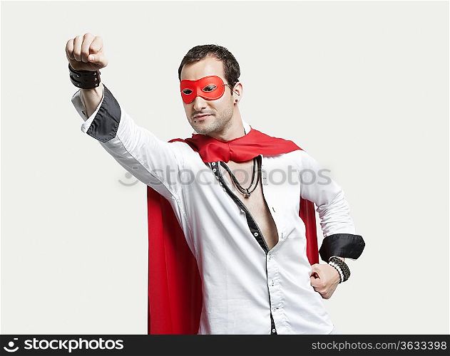 Young man wearing superhero costume against gray background