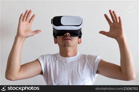 Young man wearing virtual reality goggles headset on gray background. Concept of VR, video game, future, gadgets and technology.