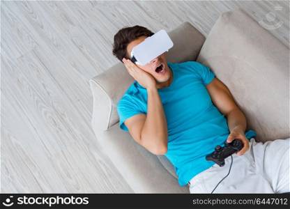 Young man wearing VR glasses relaxing on couch sofa
