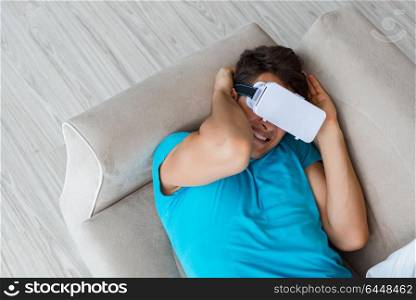 Young man wearing VR glasses relaxing on couch sofa