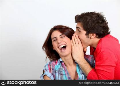 Young man whispering in his girlfriend&acute;s ear