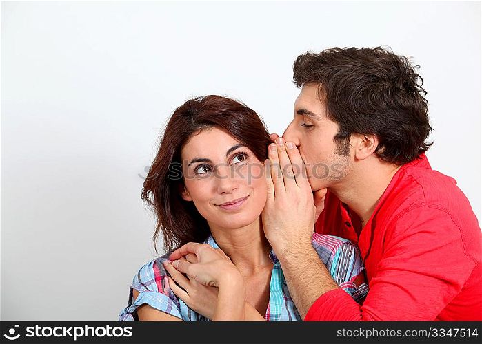 Young man whispering in his girlfriend&acute;s ear
