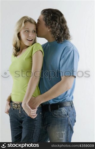 Young man whispering into a young woman&acute;s ear