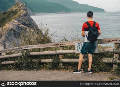 Young man with a backpack contemplating an oceanic landscape in Vizcaya, Spain