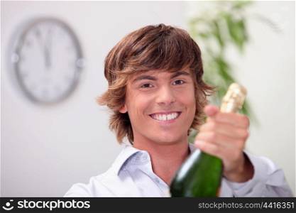 Young man with a bottle of champagne and a clock showing five to twelve