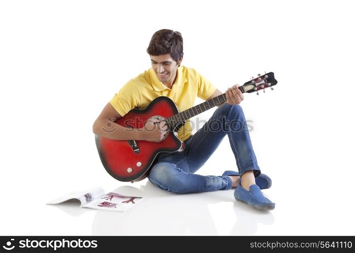 Young man with a guitar looking at a book
