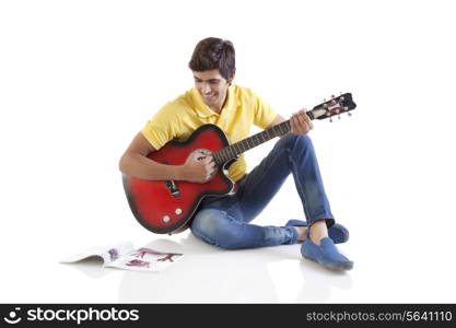 Young man with a guitar looking at a book