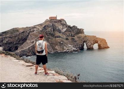 Young man with a hat in front of the Gaztelugatxe Island in Vizcaya, Spain