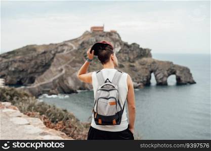 Young man with a hat in front of the Gaztelugatxe Island in Vizcaya, Spain