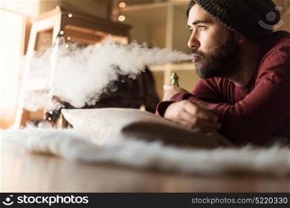 Young man with a knit cap using a vaper