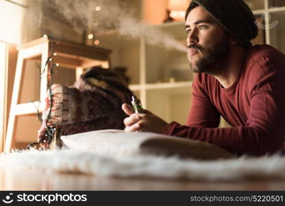 Young man with a knit cap using a vaper