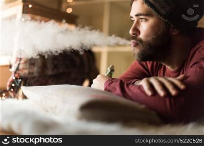 Young man with a knit cap using a vaper