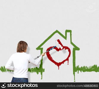 Young man with a paintbrush and family picture on the wall