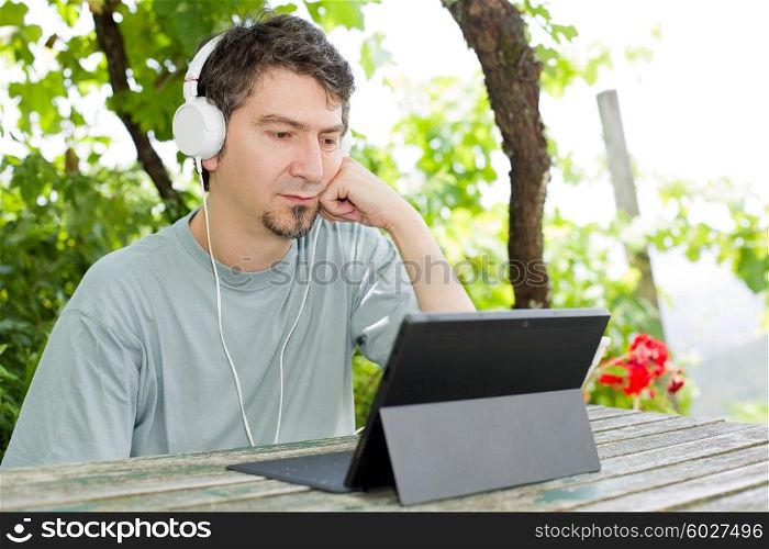young man with a tablet pc, with headphones, outdoor
