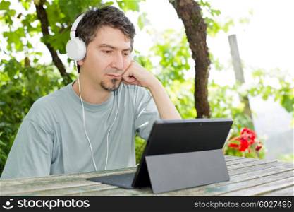 young man with a tablet pc, with headphones, outdoor