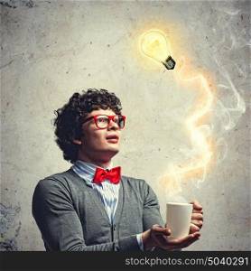 Young man with an electric bulb. Young man with smoke coming out of a cup and a bulb experimenting