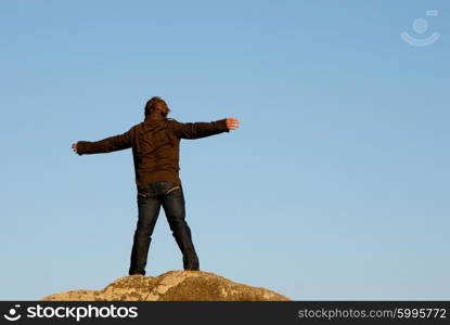 young man with arms wide open and the sky as background