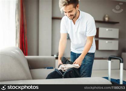 Young man with bag prepares for a journey. Fees on vacation concept. Luggage preparation. Travelling or tourism. Young man with bag, fees on vacation concept