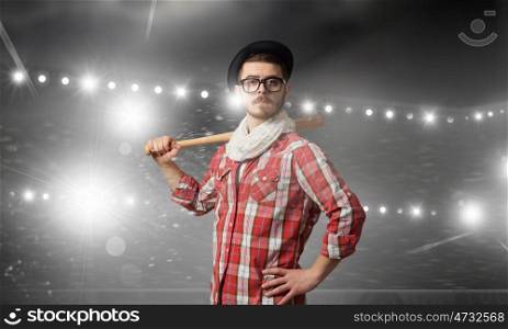 Young man with bat. Hipster guy with baseball bat in lights of stage