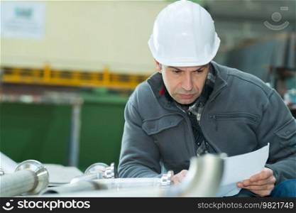 young man with blueprints working in a factory