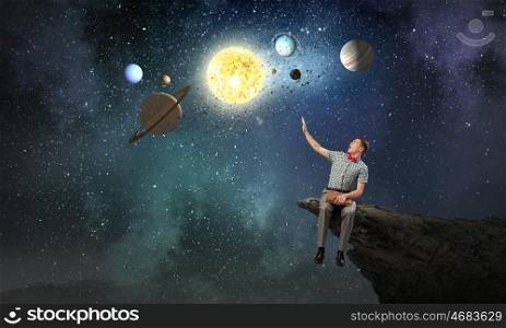 Young man with book exploring planets of sun system. Mysteries of space