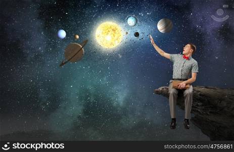 Young man with book exploring planets of sun system. Mysteries of space