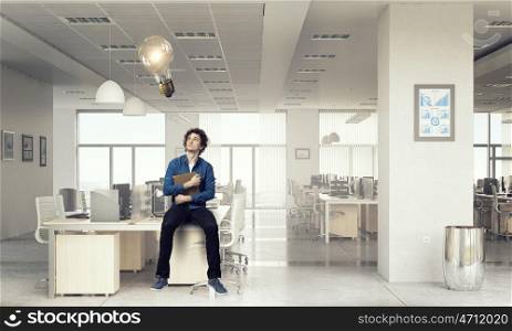 Young man with book. Guy sitting on table in modern office and reading book