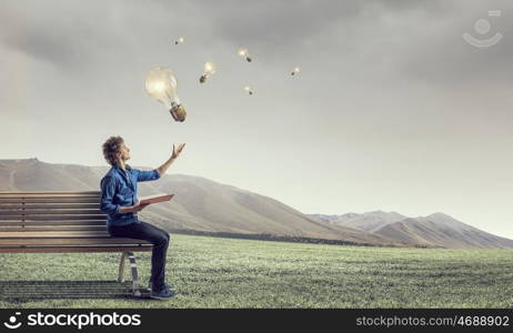 Young man with book. Guy sitting on wooden bench and reading book