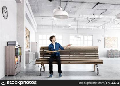 Young man with book. Guy sitting on wooden bench and reading book