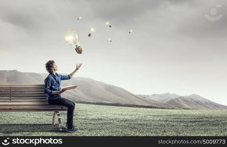 Young man with book. Guy sitting on wooden bench and reading book