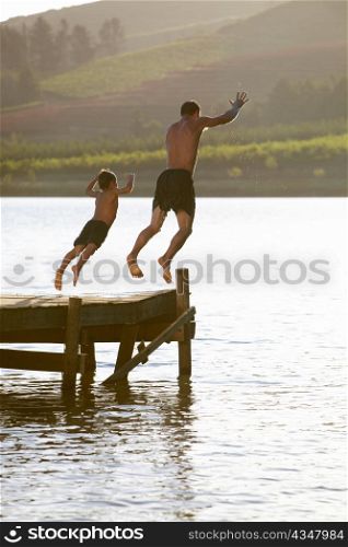 Young man with child jumping to water