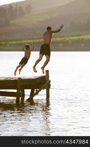 Young man with child jumping to water