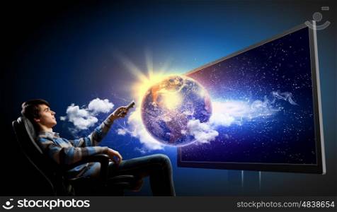 Young man with click. Young man in armchair with click watching TV