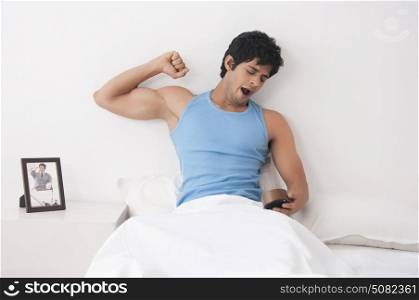 Young man with clock yawning