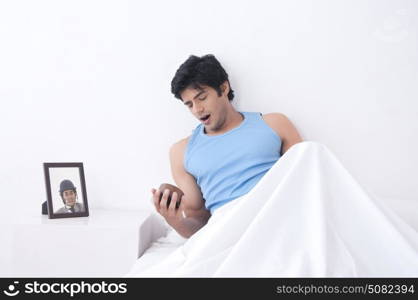 Young man with clock yawning