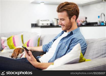 Young Man With Dog Sit On Sofa Using Digital Tablet