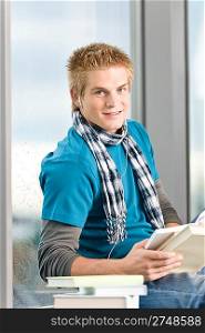 Young man with earbuds and books in modern glass building
