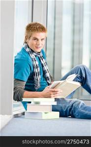 Young man with earbuds and books in modern glass building