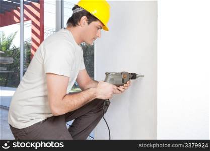 Young man with electronic drill machine working